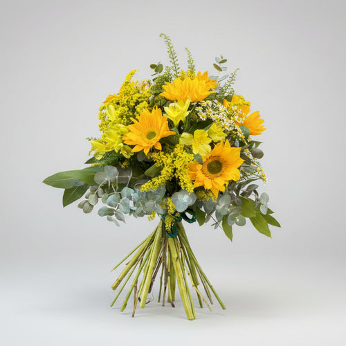 ramo de flores natrales compuesto de girasoles, solidazgo y alstromelias amarillas con verdes de eucalipto atado por un lazo verde.