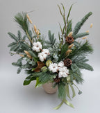 centro navideño en color blanco y verdes con abeto y pino natural, con flores de algodón y piña seca y frutos deshidratados  sobre una base beis cerámica. 