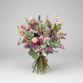 ramo de flores secas en color rosa, blancos y verdes, compuesto por flores de siemprevivas, limonium y toques de espiga y cebada natural con flores de campo en seco. el ramo está atado con una cuerda de yute marrón con sus tallos limpios. toda la imagen está sobre un fondo blanco en luz neutra.