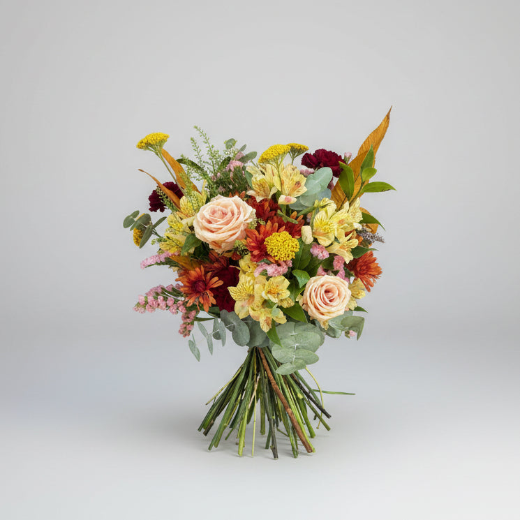 ramo castaño es un ramo propio de temporada otoñal que lleva colores como el burdeo, amarillo, toques salmon y rosa donde predomina el follaje de hojas de castaño preservado y eucalipto natural, atado con rafia en color verde sobre un fondo blanco
